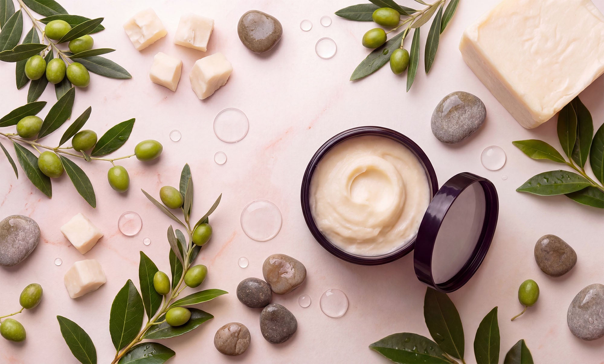 Jar of cream with olive leaves and stones on a light background