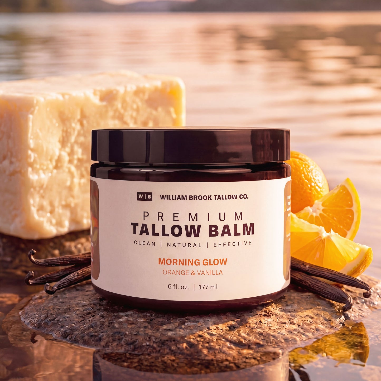 Jar of William Brook Tallow Co. Premium Tallow Balm with soap and oranges on a reflective surface.